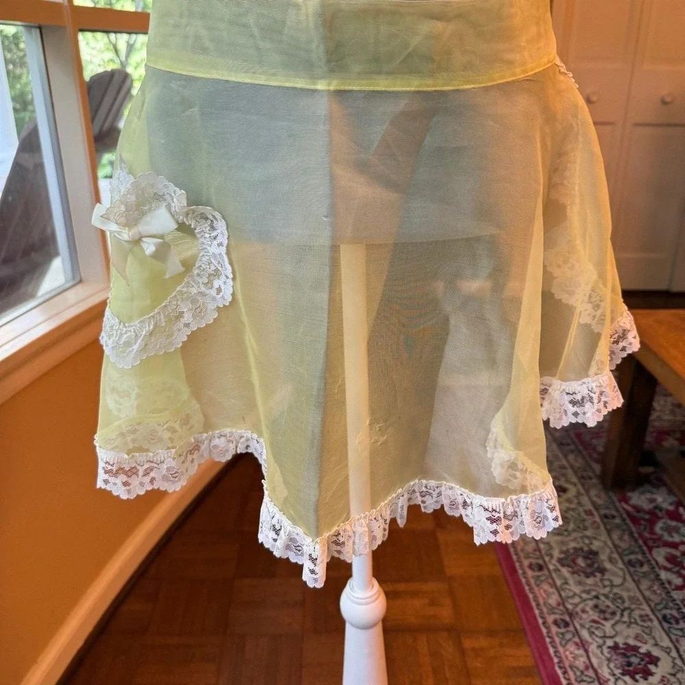 Vintage sheer yellow apron with ornate white lace trim and a bow-accented pocket